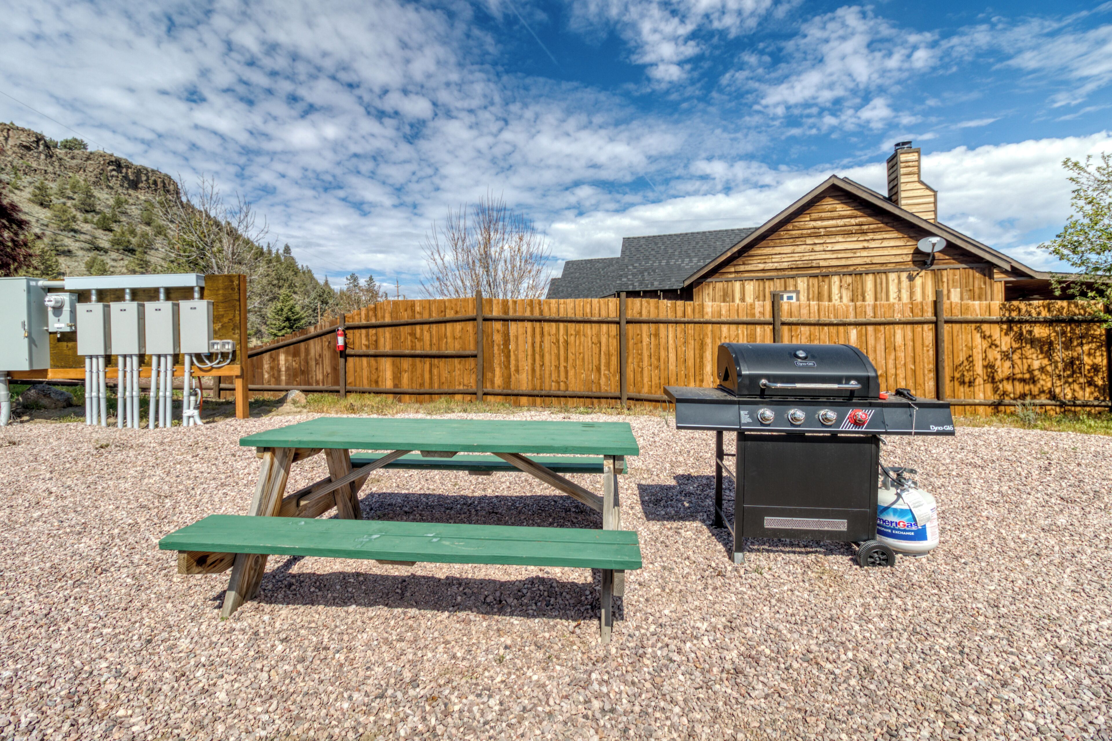 Un bâtiment en bois avec un barbecue et une table de pique-nique à l’avant.