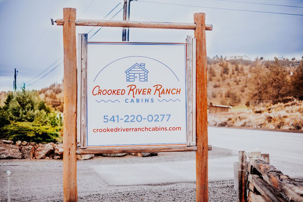 A signboard for Crooked River Ranch Cabins with contact information and a website URL.