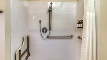 A shower area with a grab bar, a handheld showerhead, and a shower curtain.