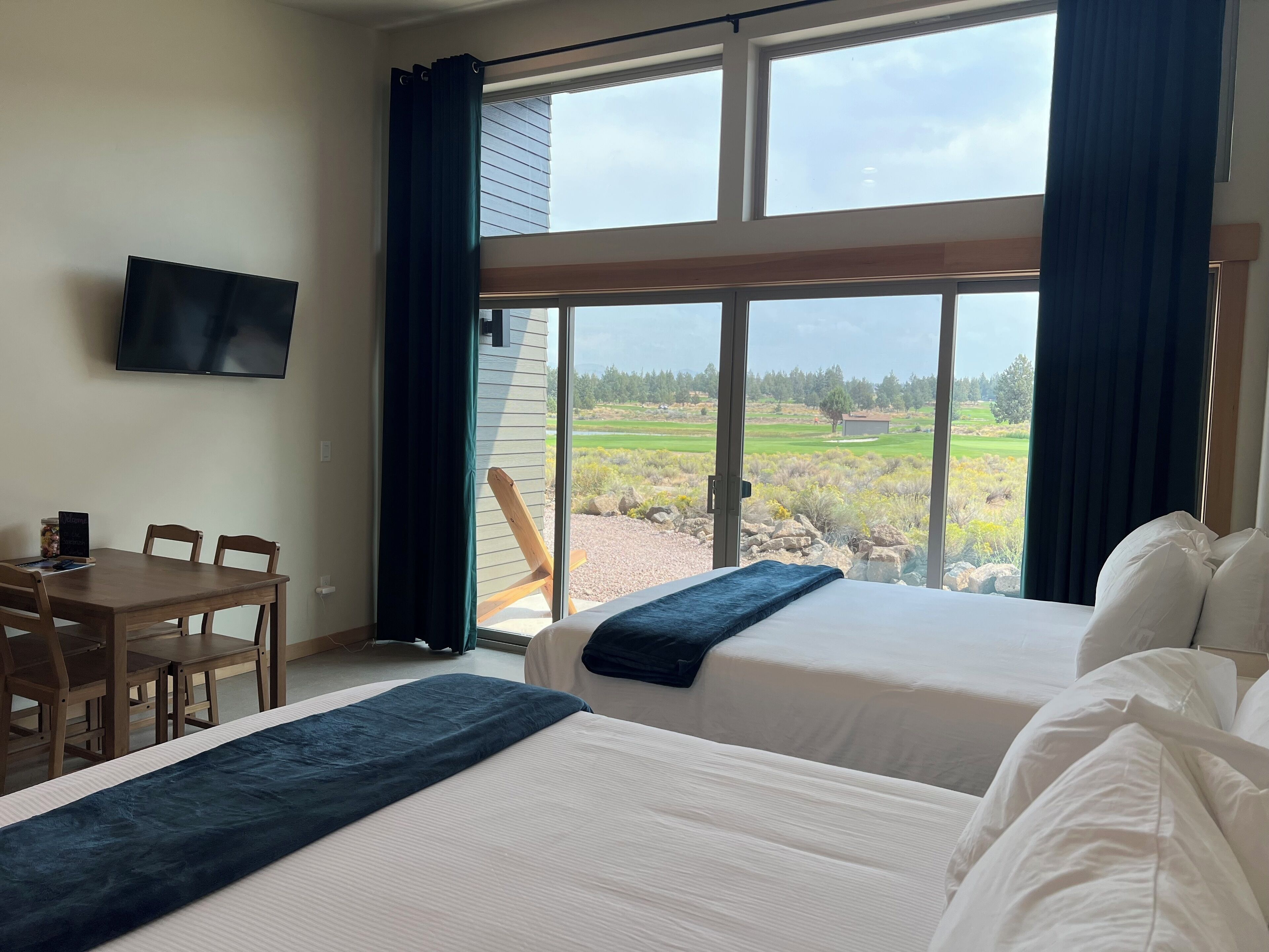 A hotel room with two beds, a desk, and a TV.