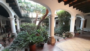 A courtyard with arches, potted plants, and a tiled floor.