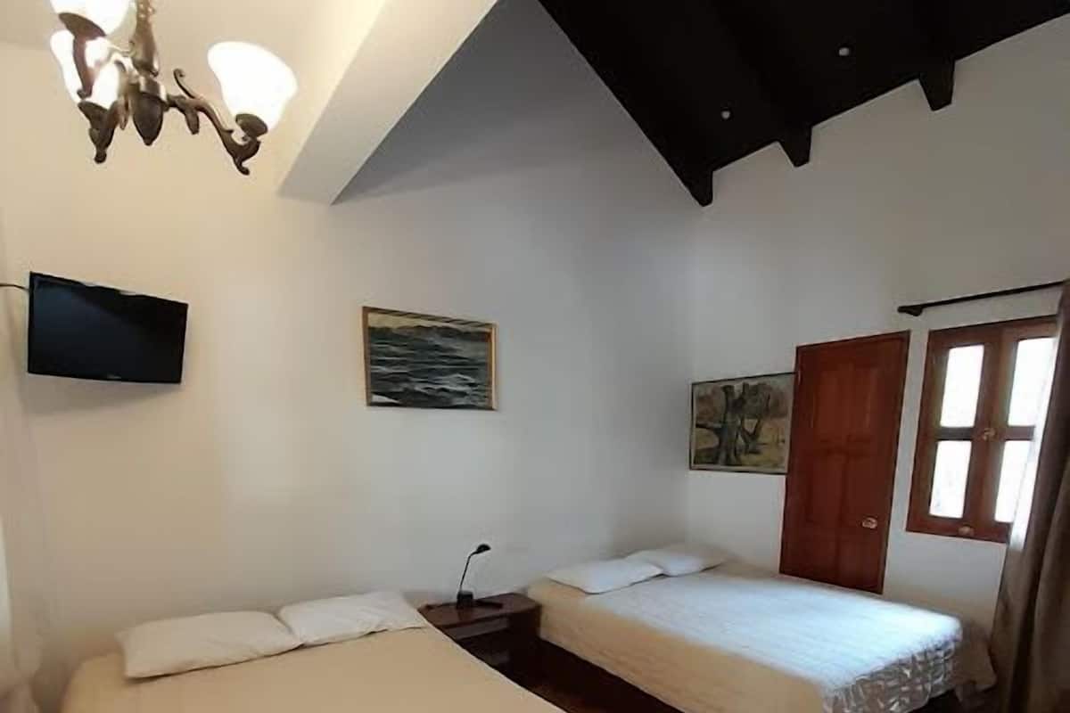 A room with two beds, a TV, and artwork on the walls.