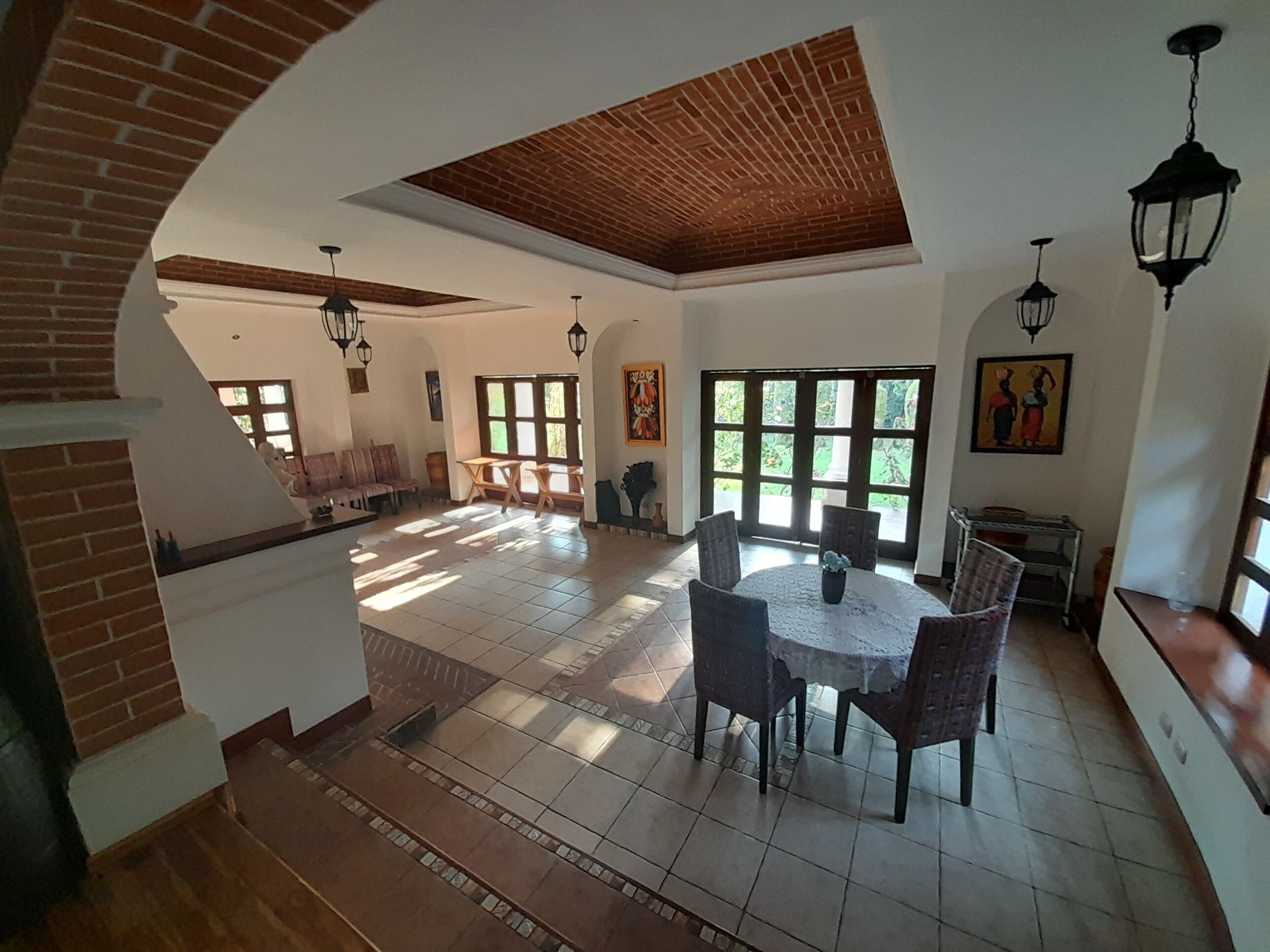 Un salón amplio con techo alto, una mesa de comedor con sillas, un sofá y una zona de cocina con estufa y armarios.