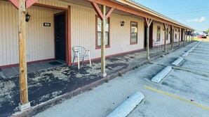 Eine Reihe von Motelzimmern mit jeweils einem Stuhl davor, mit den Nummern 109, und einem Parkplatz im Vordergrund.