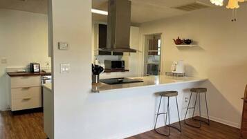 A modern kitchen with a central island, bar stools, and a microwave.