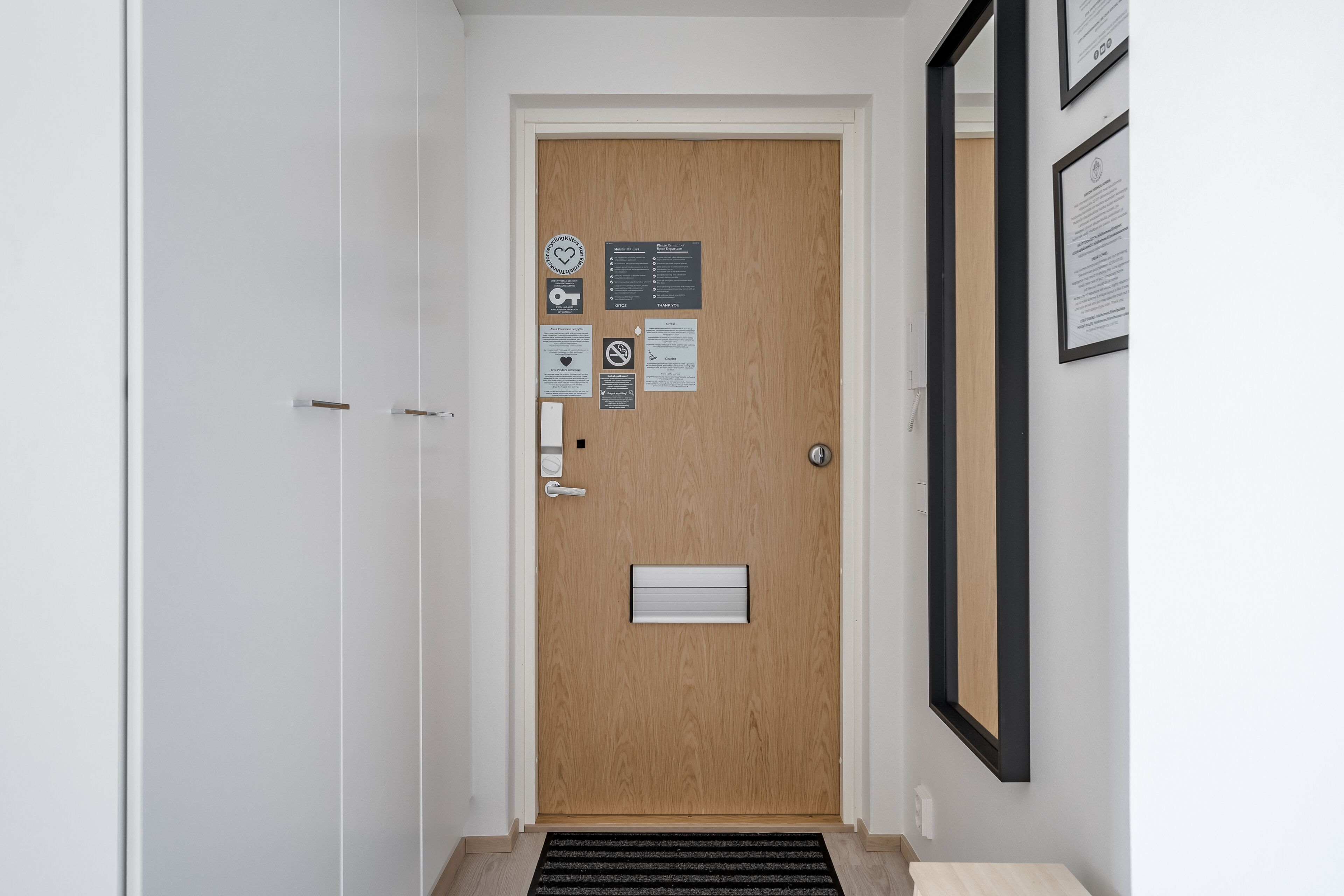 A wooden door with a mail slot, a handrail, and a wall-mounted mirror.