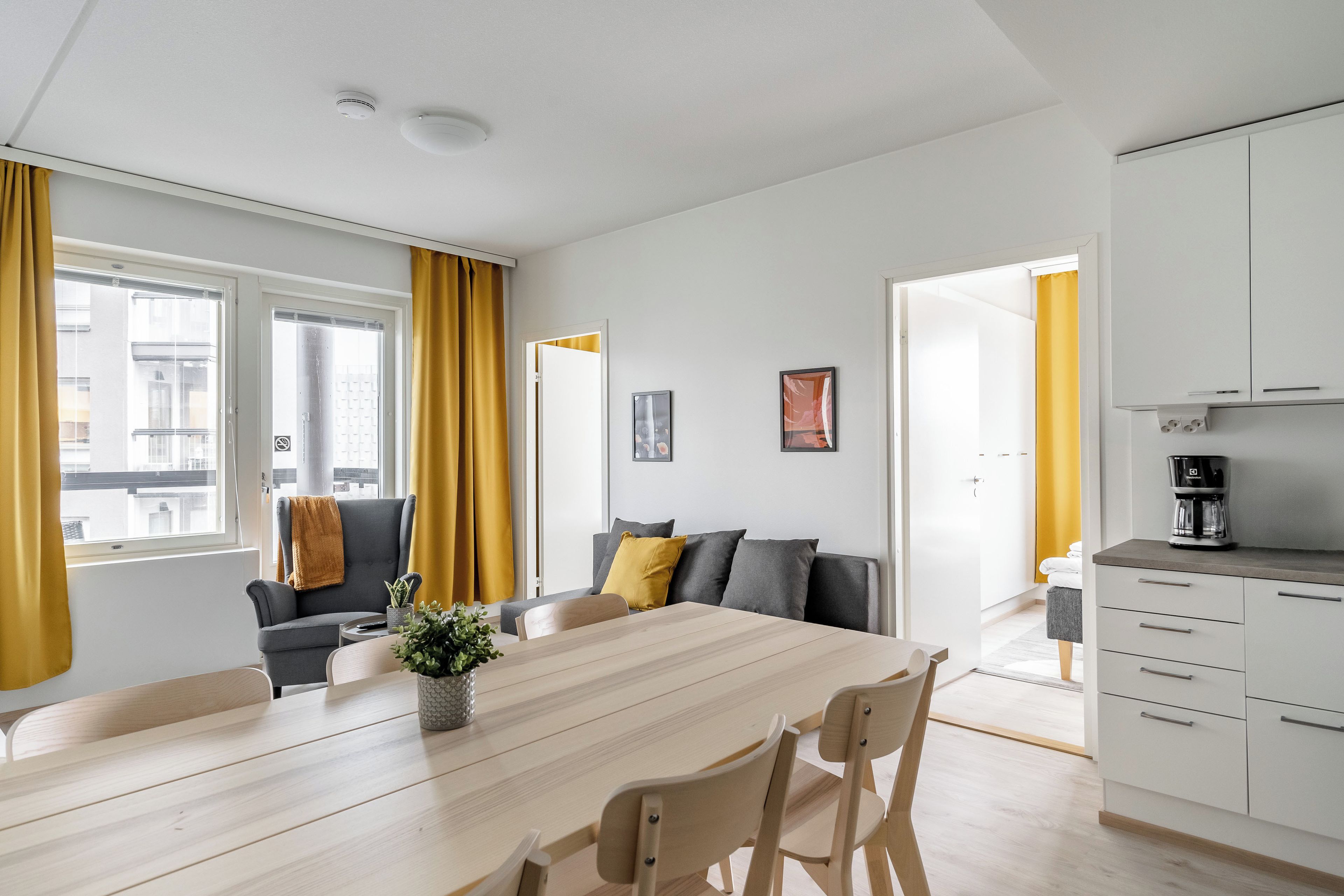 A modern living room with a dining table, sofa, and kitchen area.