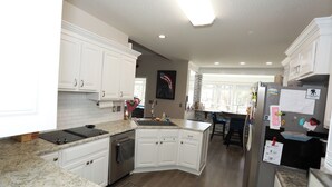 A modern kitchen with white cabinets, granite countertops, a built-in oven, and a refrigerator. - Golf Course Retreat w/Sunroom, Pool Table & Patio (WARNER ROBINS)