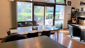 A dining area with a table, chairs, and a chandelier. There is a sliding glass door leading to an outdoor patio with a view of a garden and buildings. - Flagstaff Golf Course Condo - 9th Green of Continental Country Club (Flagstaff)
