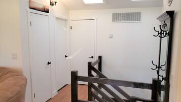 A hallway with a wooden staircase, white doors, and a skylight.