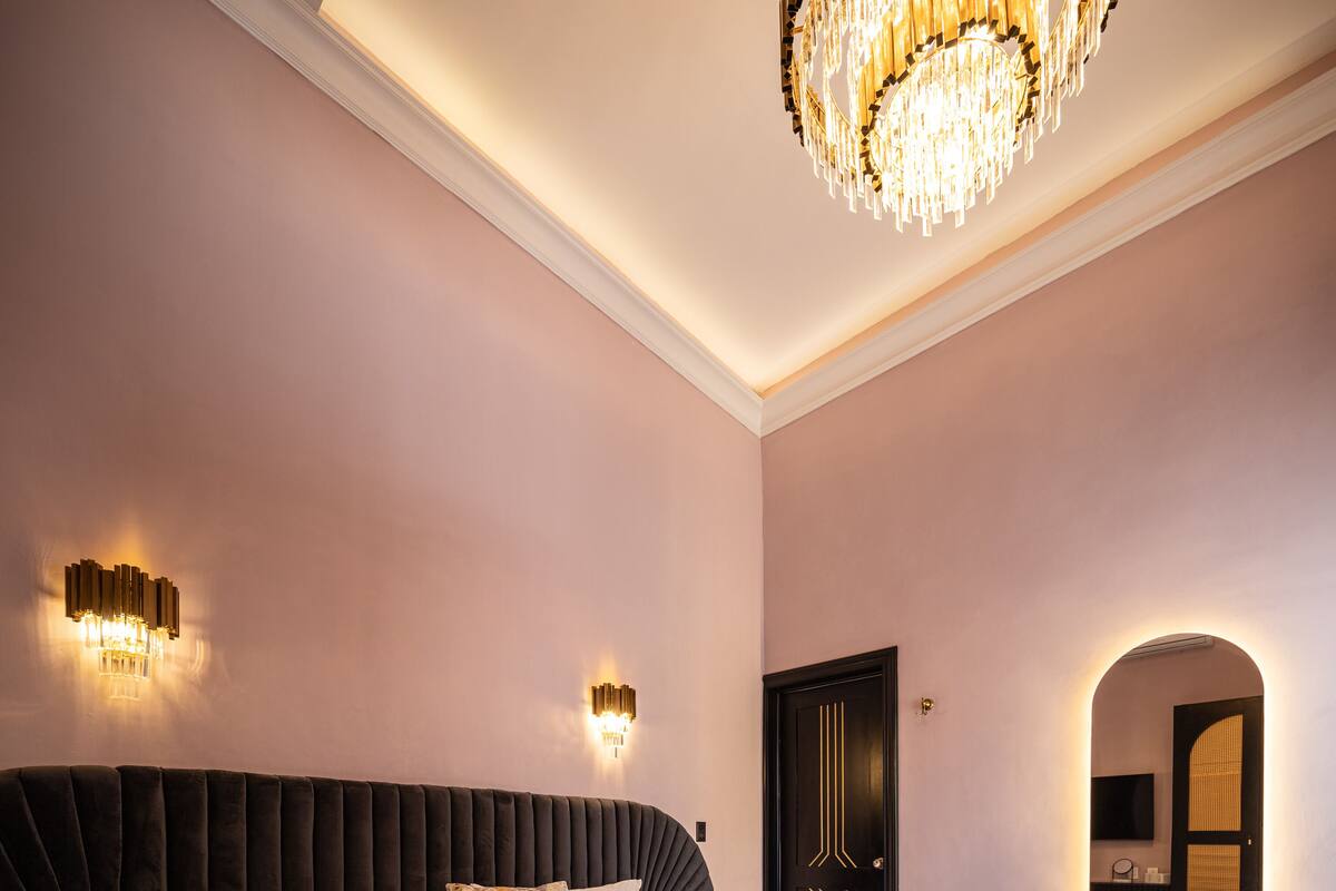 Une chambre spacieuse avec un grand lit, un lustre et des appliques murales.
