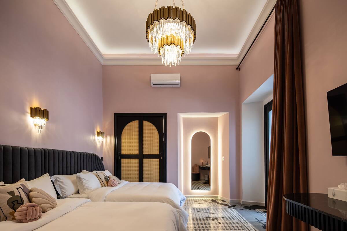 Une chambre à coucher avec un grand lit, un lustre et un miroir.