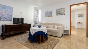 Ein Wohnzimmer mit Fernseher, Sofa, Couchtisch und Kunstwerken an den Wänden.
