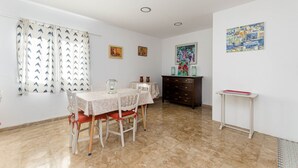 Ein Essbereich mit einem Tisch für vier Personen, einem Schrank und einem kleinen Tisch mit roter Ablage.