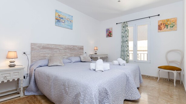 Ein Schlafzimmer mit einem großen Bett, einem Nachttisch mit Lampe, einem Sessel und Bildern an den Wänden.