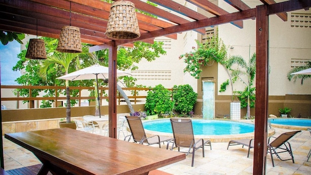 Eine Terrasse im Freien mit Pool, Holztischen, Stühlen und hängenden Körben.