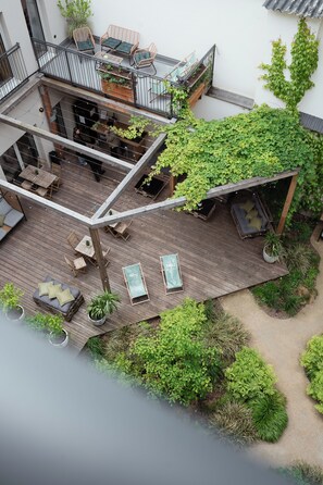 A rooftop terrace with wooden flooring, seating areas, and a variety of plants. - Urban Jungle Apartments (Vienna)