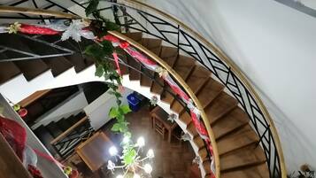Un escalier en colimaçon avec des marches en bois et une rampe en métal, décoré de rubans rouges et blancs et de verdure.