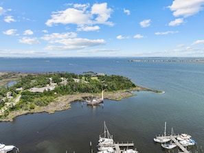 Una marina con imbarcazioni ormeggiate, una piccola isola con edifici e un cielo sereno.