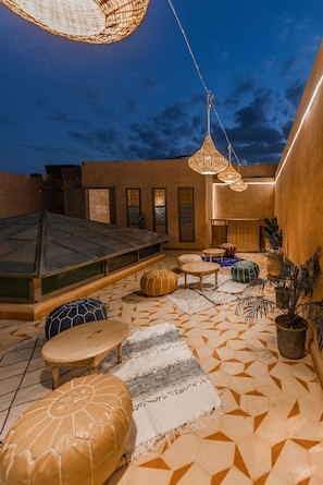 An outdoor seating area with hexagonal patterned flooring, wooden furniture, and hanging wicker lamps. - l'émeraude de la Médina (Marrakech)