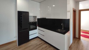 Une cuisine moderne avec des armoires blanches, un plan de travail noir et un four encastré.