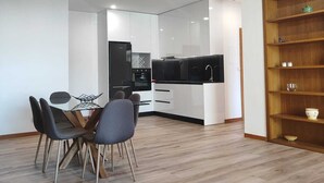Une cuisine moderne avec des meubles blancs, un plan de travail noir et un coin repas comprenant une table et des chaises.