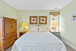 Une chambre à coucher comprenant un lit, deux tables de chevet, une armoire en bois et deux lampes fixées au mur.