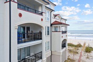 Un immeuble à plusieurs étages doté de balcons donnant sur une plage.