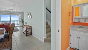 A spacious living area with a view to the outside, a staircase, and a bathroom with a large mirror and shelves. - 3BR Oceanfront Townhome on North Topsail Beach (North Topsail Beach)