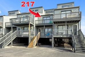 A multi-story residential building with balconies, numbered 217 and 218, featuring external staircases and a covered entrance. - 3BR Oceanfront Townhome on North Topsail Beach (North Topsail Beach)