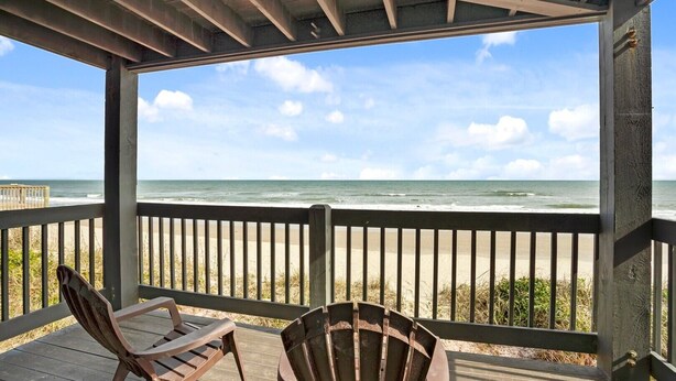 A covered deck with a view of the ocean, featuring two wooden chairs and a small table. - 3BR Oceanfront Townhome on North Topsail Beach (North Topsail Beach)