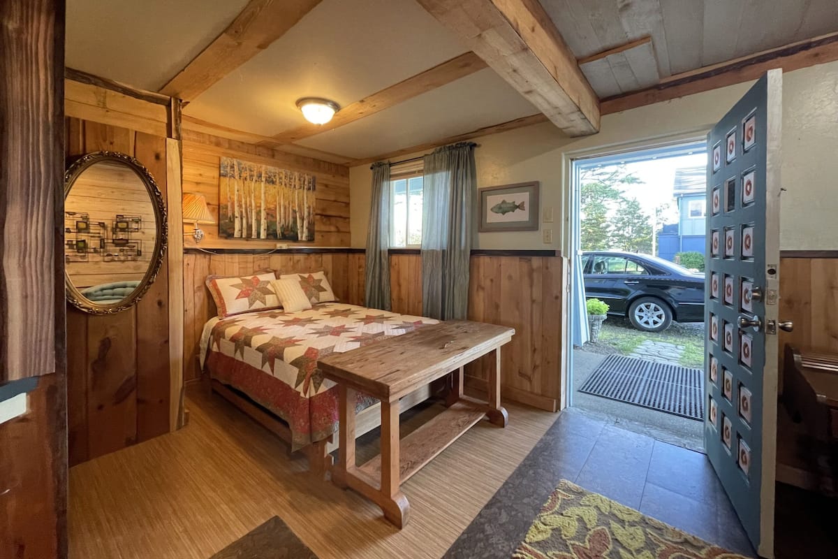 A cozy bedroom with a wooden bed, a mirror, and a door leading outside.