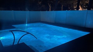 A swimming pool with a blue light feature and a water fountain.