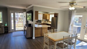 A spacious kitchen with wooden cabinets, a dining table with chairs, and a large window.