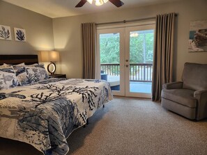 A bedroom with a bed, a chair, a nightstand, and a balcony with curtains. - Quiet Windy Hill Retreat | Pool, Game Room, Pets (North Myrtle Beach)
