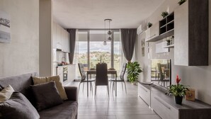 Una sala moderna con sofá, mesa de comedor, sillas y vistas al exterior.