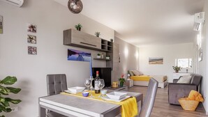 Una sala de estar moderna con comedor, muebles grises y una chimenea.