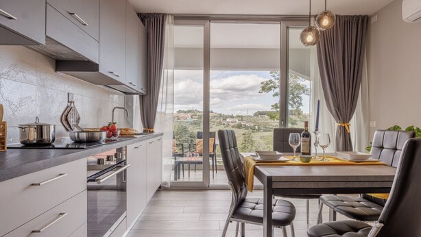 Una cocina moderna con comedor, ventanas amplias y vista al campo.