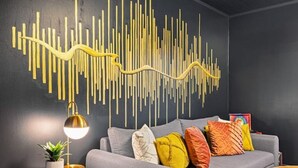 A modern living room with a grey sofa, colorful cushions, a wall art piece, a small round table, and a floor lamp. - Pet-Friendly, Sauna, Hot Tub, Game Room, Two Firepits, Sleeps 12 (Asheville)