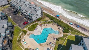 Vue aérienne d’un hôtel situé sur la côte, doté d’une piscine, d’un accès à la plage et de plusieurs bâtiments.