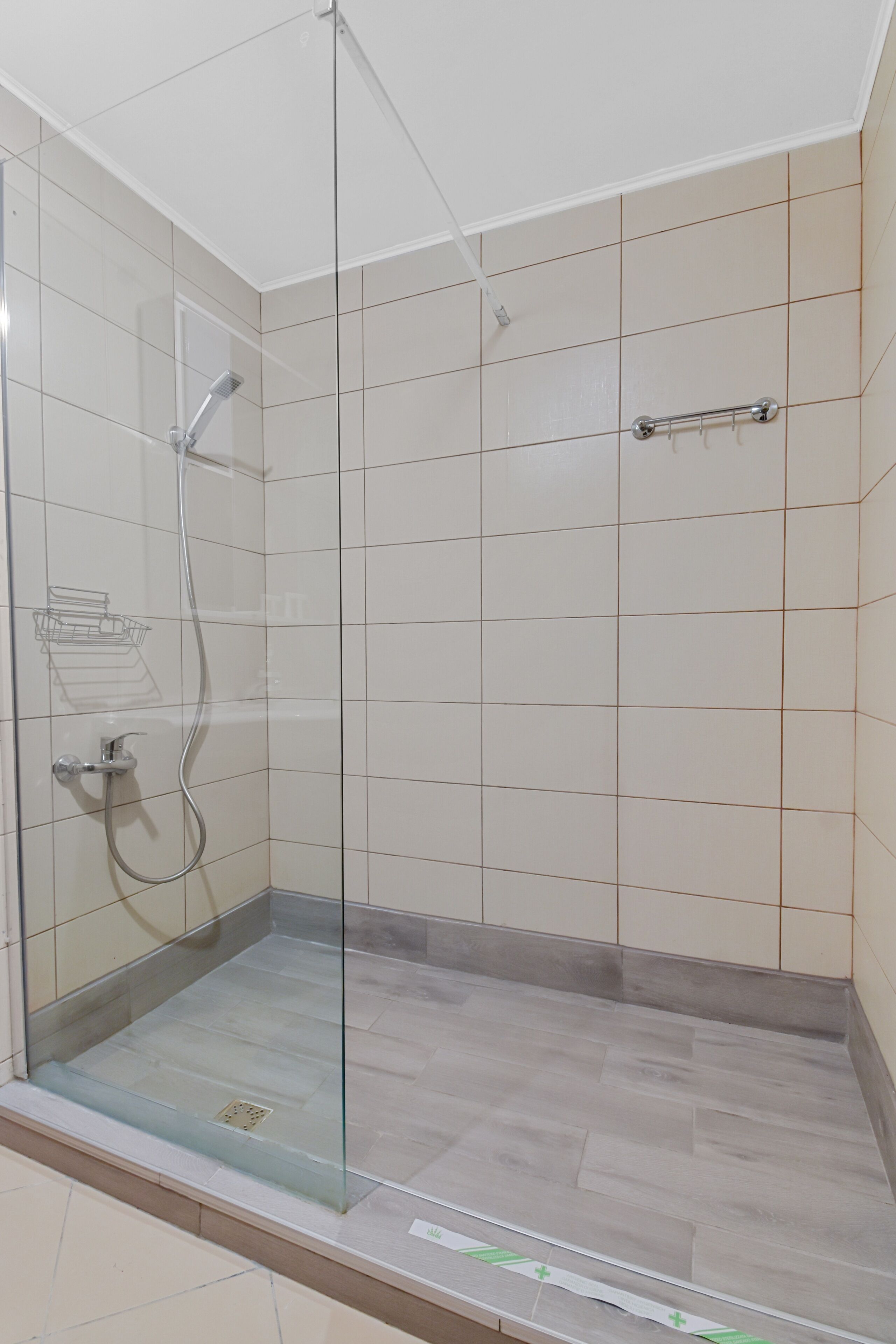 A glass-enclosed shower with a handheld showerhead and a wall-mounted faucet.