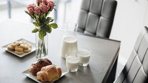 Une table à manger avec des pâtisseries, du lait et des fleurs.