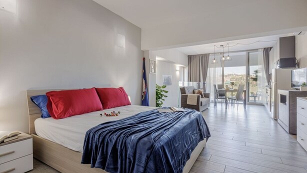 Une chambre moderne avec un grand lit, un bureau et un balcon offrant une vue agréable.