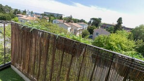 Ein Balkon mit Bambuszaun mit Blick auf eine Wohngegend mit Häusern und Bäumen.