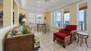 A spacious living area with a view of the ocean, a ceiling fan, and a dining table with chairs. - 5BR Oceanfront Home on North Topsail Sleeps 15 - Pool & Hot Tub (North Topsail Beach)