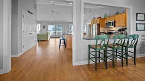 A spacious kitchen with wooden cabinets, a microwave, and a large island with bar stools. - 5BR Ocean View House on North Topsail Beach - Pool (North Topsail Beach)