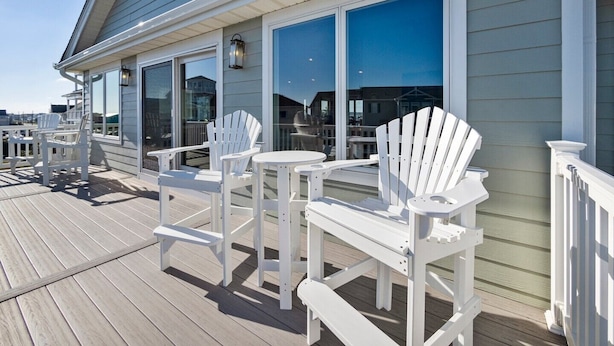 A wooden deck with white Adirondack chairs and a table, overlooking a body of water. - 5BR Ocean View House on North Topsail Beach - Pool (North Topsail Beach)