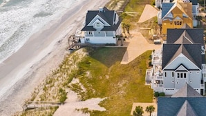A coastal residential area with houses along the beach, featuring a mix of architectural styles and a clear view of the ocean. - 4BR Oceanfront House - Sleeps 15 on North Topsail Beach - Pool (North Topsail Beach)