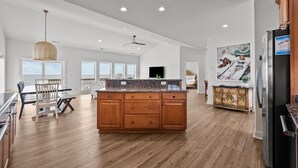 A spacious kitchen with a central island, wooden cabinets, and a modern refrigerator.