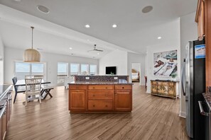Eine geräumige Küche mit einer zentralen Kochinsel, Holzschränken und einem modernen Kühlschrank.